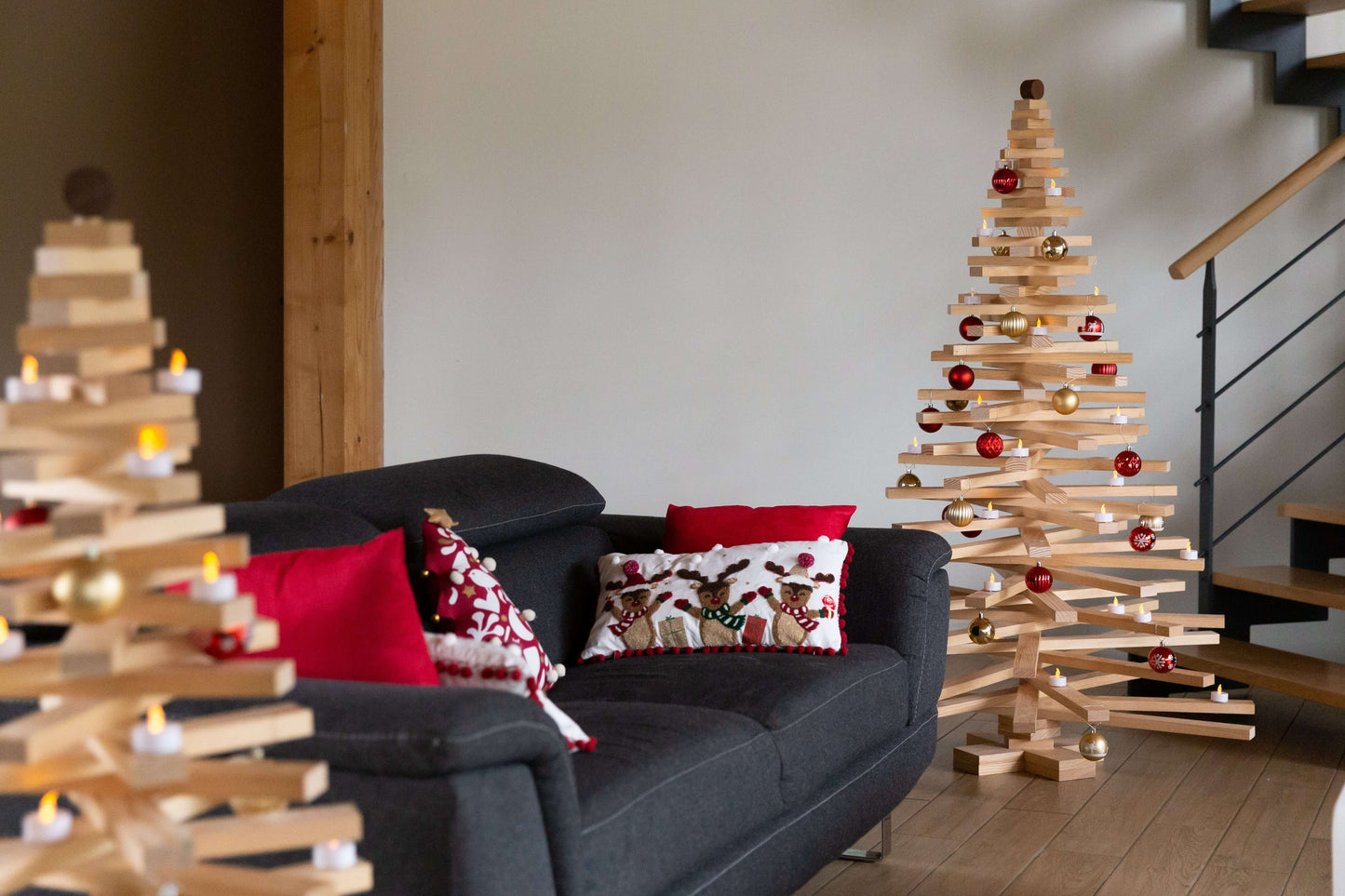 Décor intérieur avec sapin de Noël en bois 160 cm Sapinou Maxi et coussins rouges dans un salon élégant.