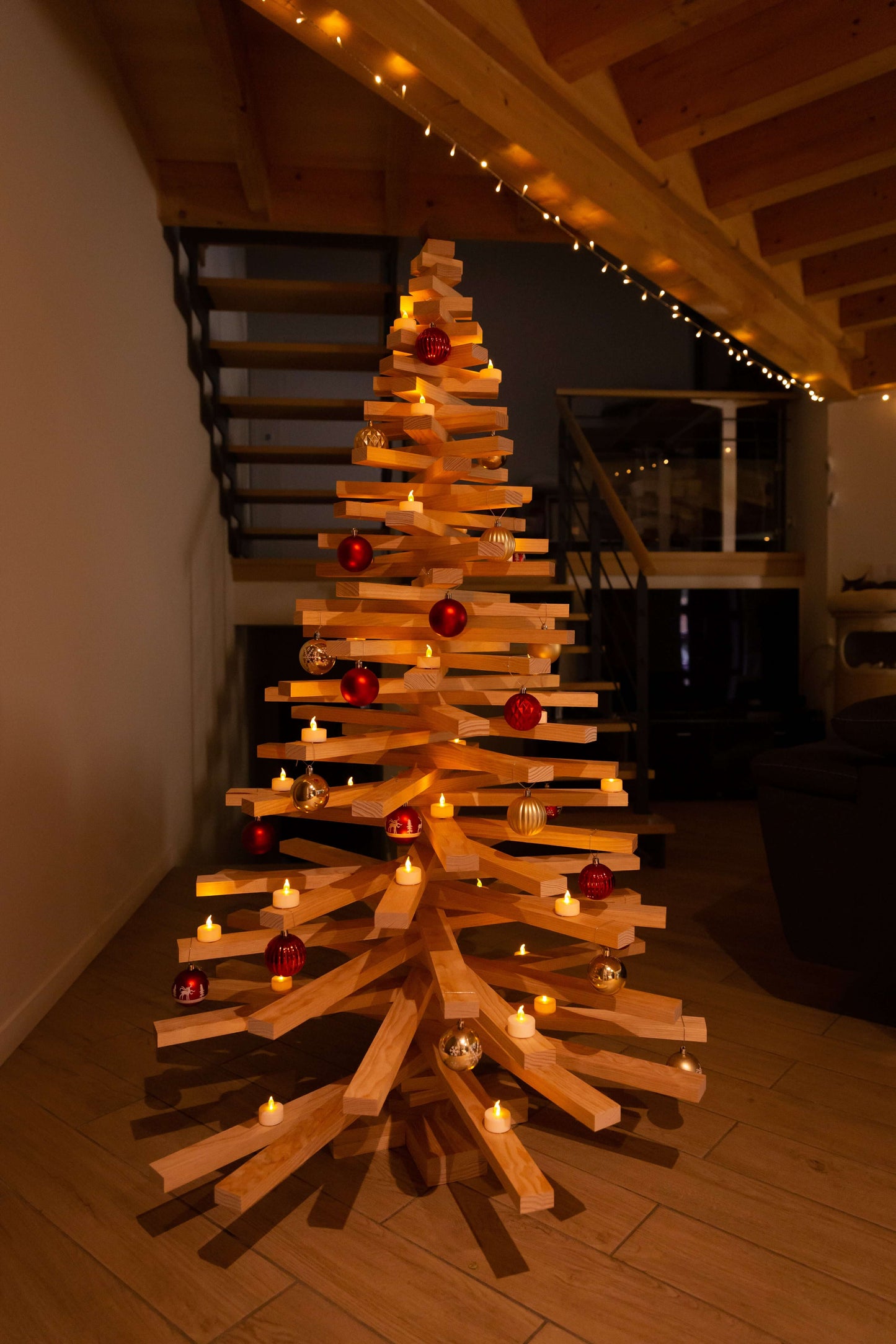 Sapin de Noël en bois 160 cm décoré avec des boules rouges et des bougies, dans un intérieur chaleureux.