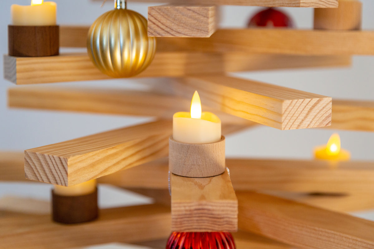 Bougeoir en bois clair avec bougie led posé sur une lame du sapin en bois
